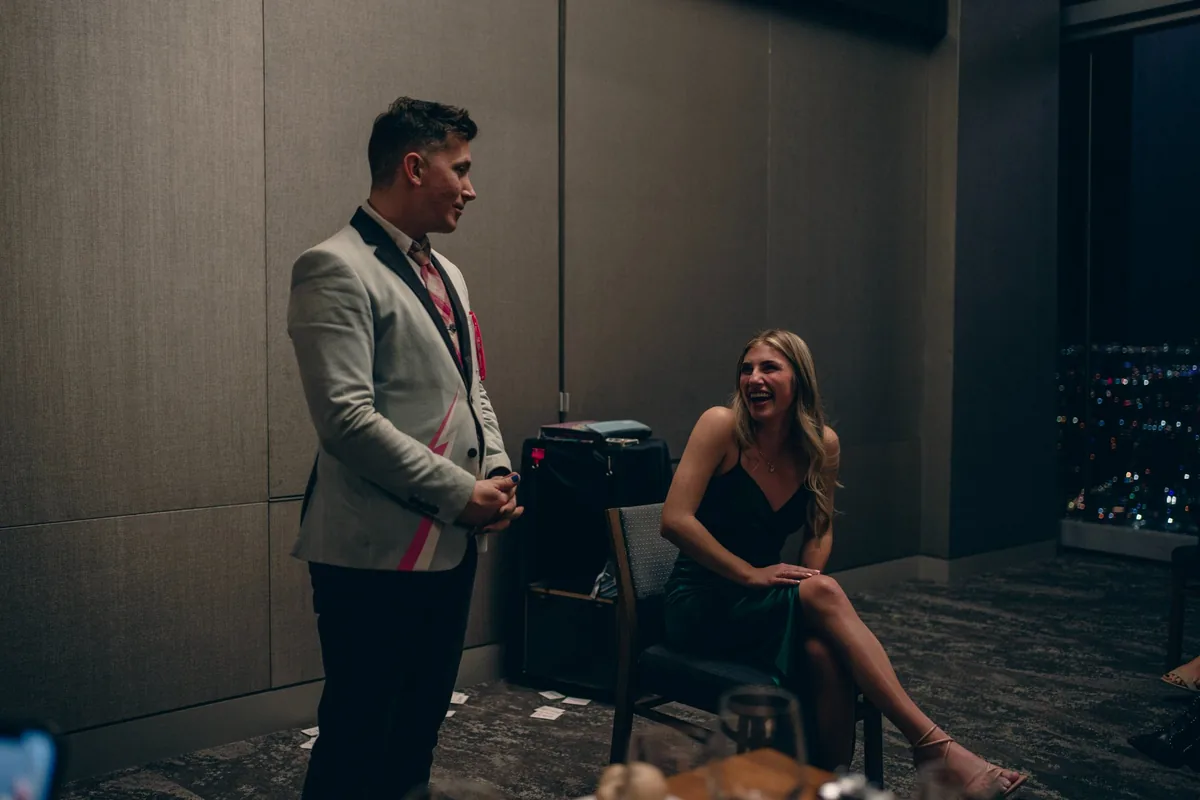Joe Coover holding Bicycle cards raised against floor-to-ceiling windows